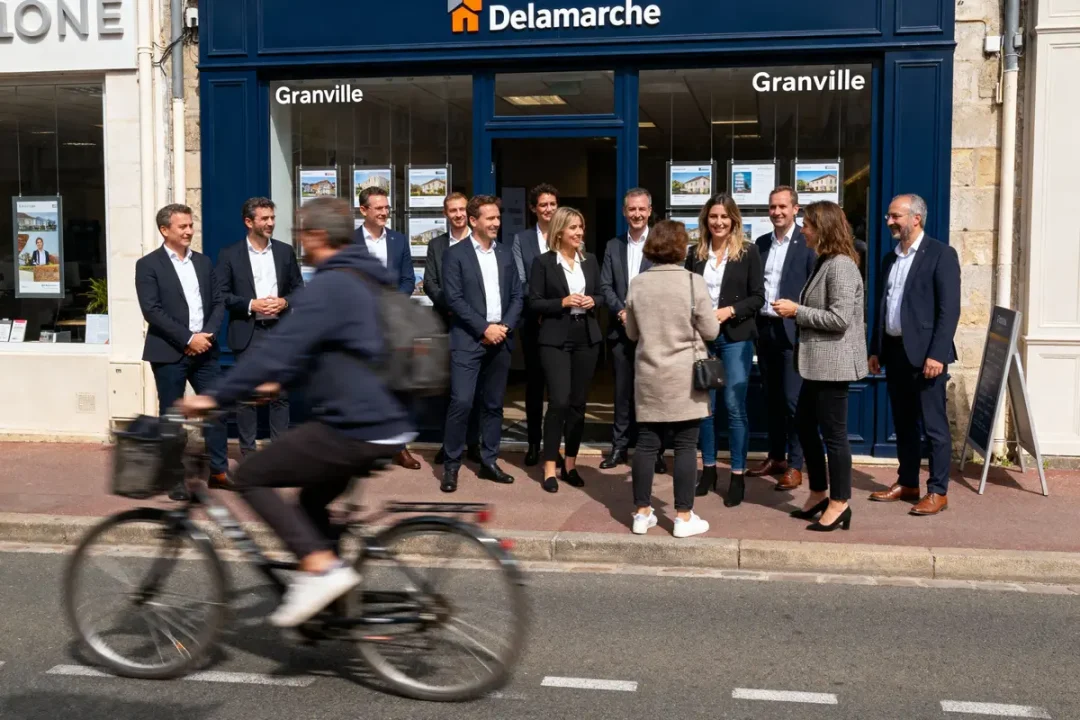 Groupe de personnes en tenue professionnelle devant une agence immobilière, cycliste flou passant devant.