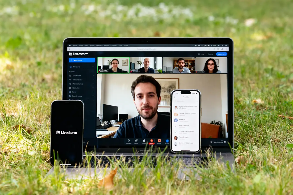 Ordinateur portable en visioconférence sur l'herbe, smartphone affichant événement Livestorm, écran partagé avec six participants.