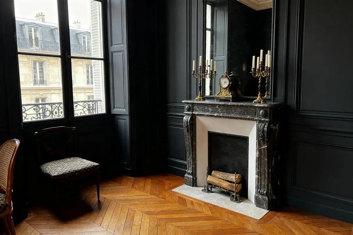 Intérieur élégant avec moulures et cheminée en marbre de couleur anthracite, parquet en bois.