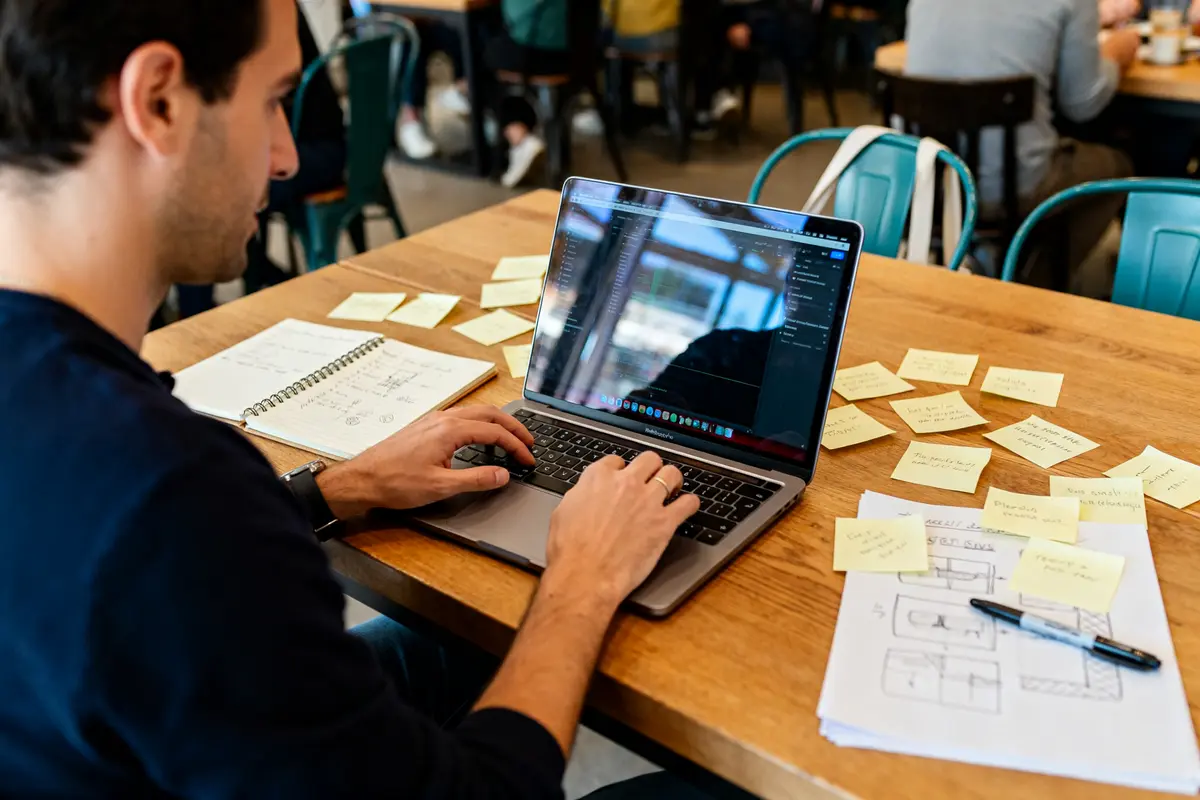 Homme travaillant sur ordinateur avec post-it pour le business mag entreprendre dans un café
