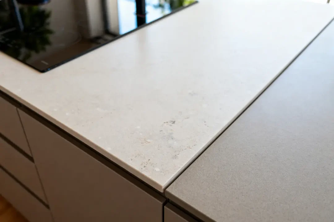 Plan de travail de cuisine en Dekton beige avec plaque de cuisson noire intégrée