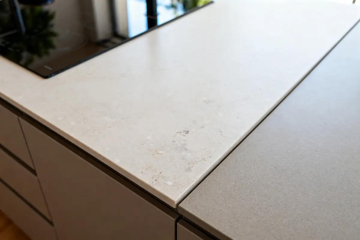 Plan de travail de cuisine en Dekton beige avec plaque de cuisson noire intégrée