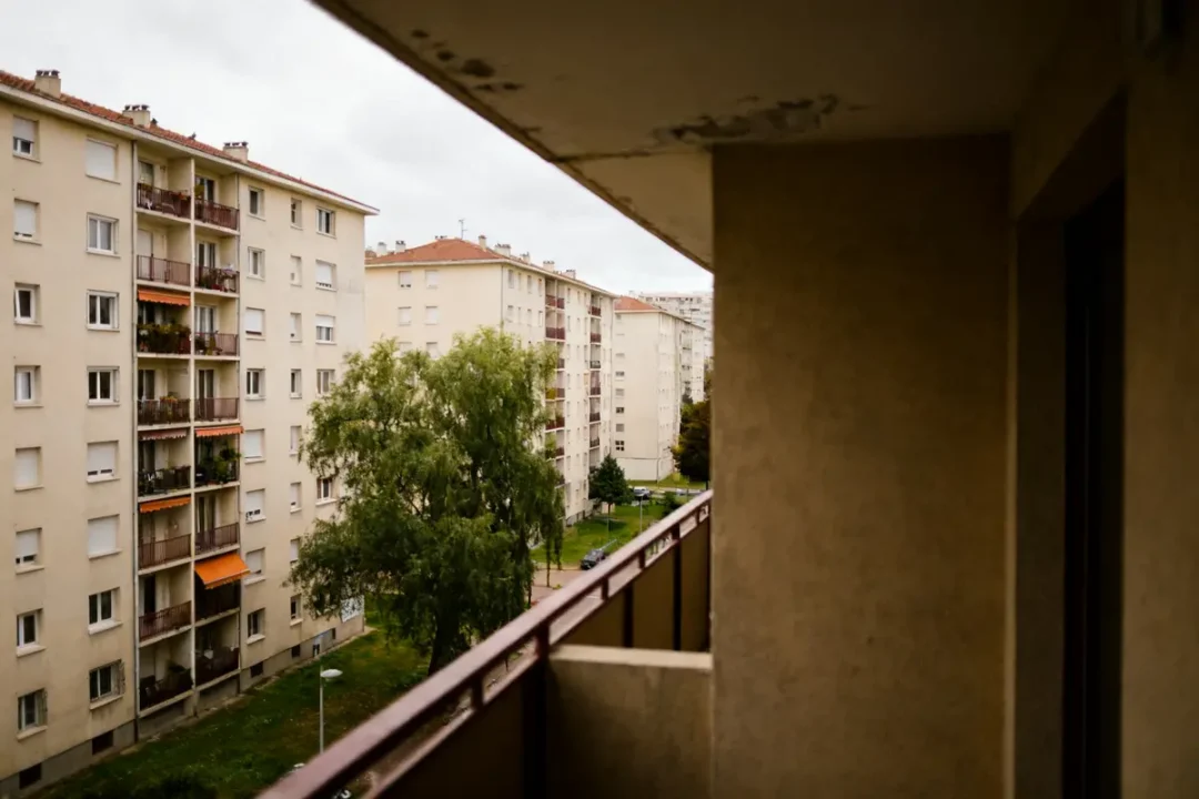Vue sur des immeubles HLM avec balcons et arbres depuis un autre bâtiment