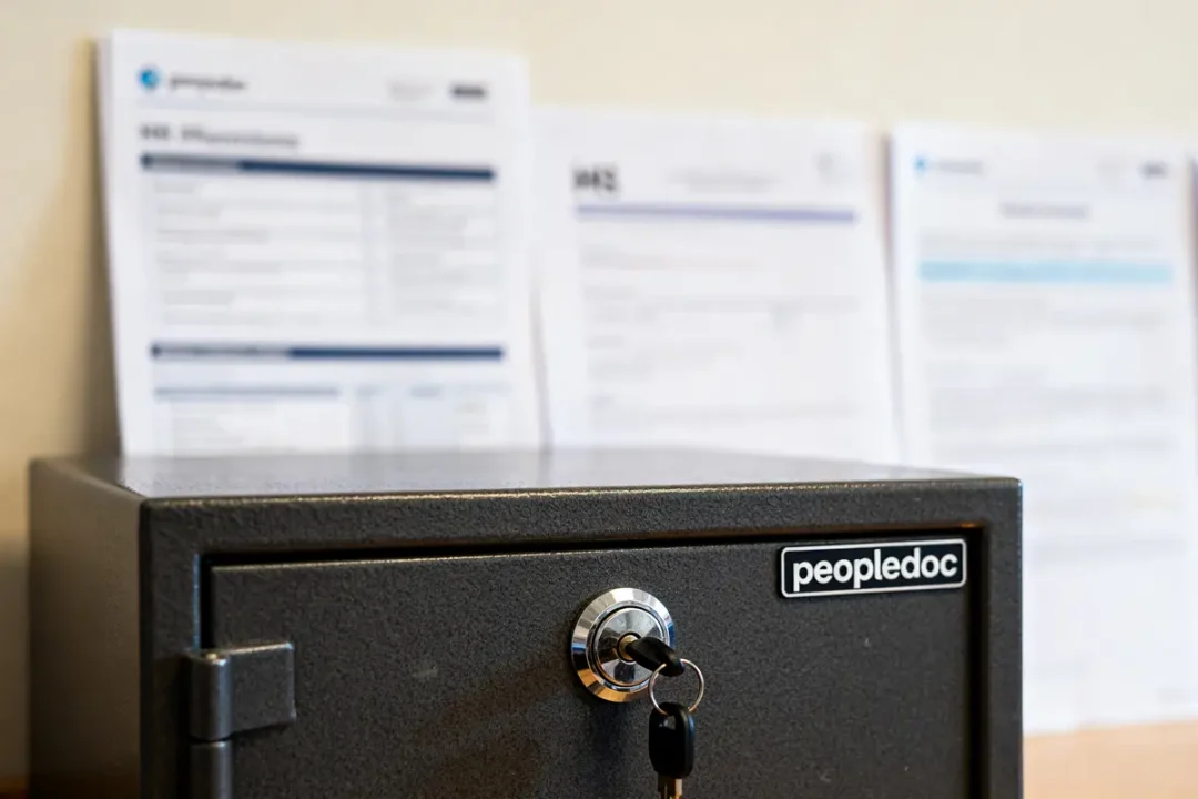 Coffre sécurisé peopledoc avec clés, documents flous en arrière-plan sur un bureau