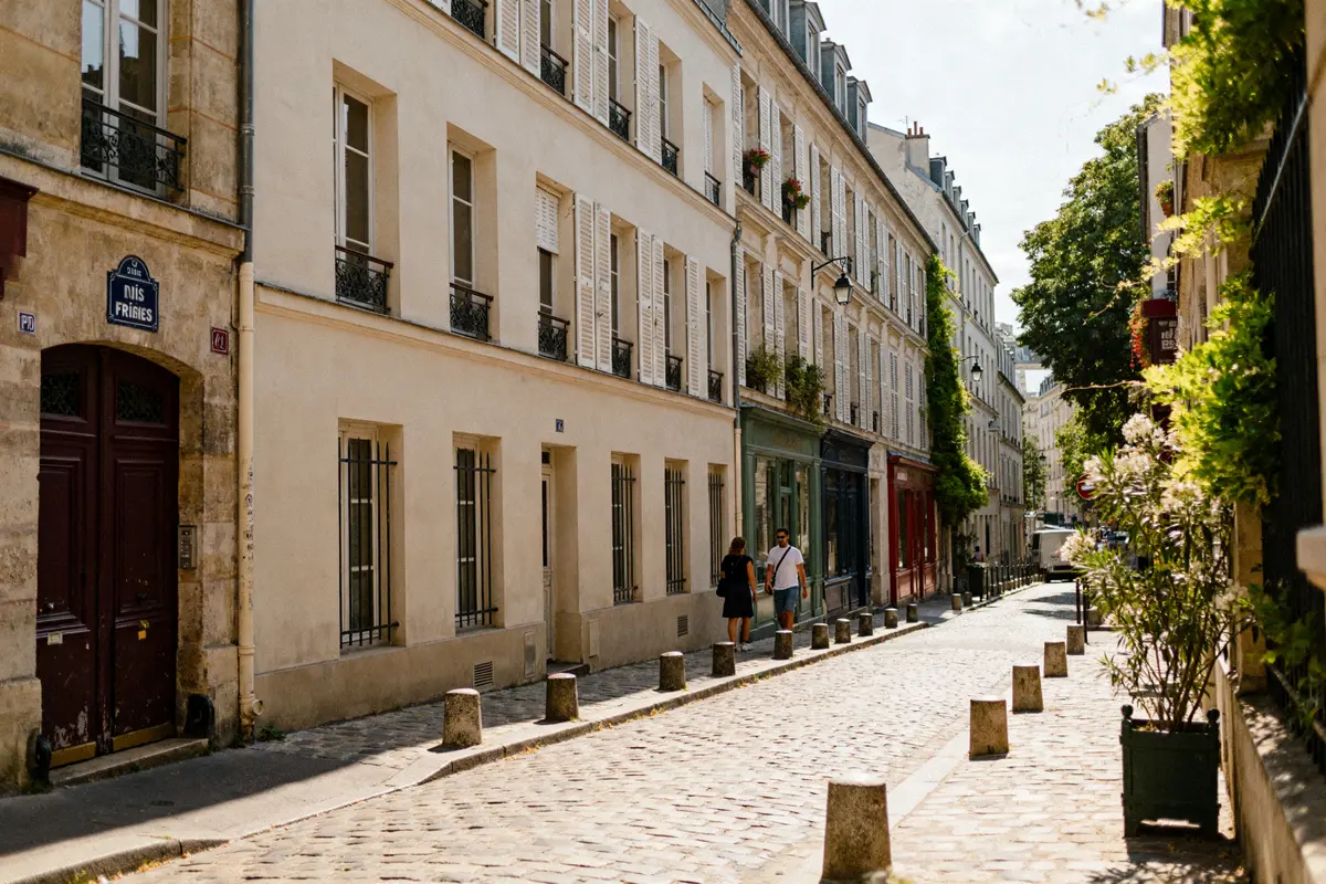 Bâtiments parisiens et passants dans la rue des Trois Frères sous le soleil d'été