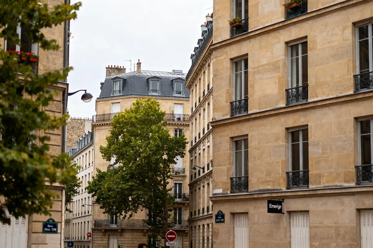 Rue parisienne avec bâtiments classiques et signalétique Emerige au coin de la rue
