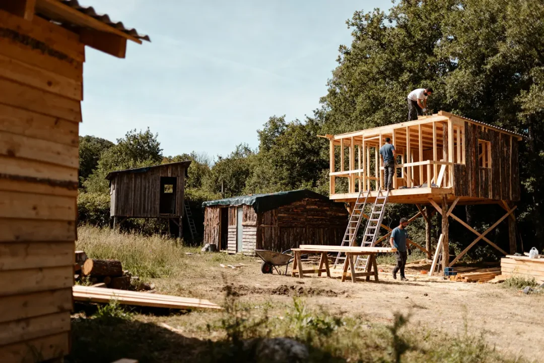 Construction de cabanes en bois dans un environnement naturel en forêt qui paye