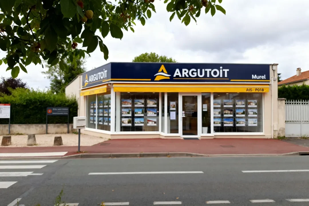 Agence immobilière l'Argutoit avec vitrine, signalétique bleue sous feuillage urbain