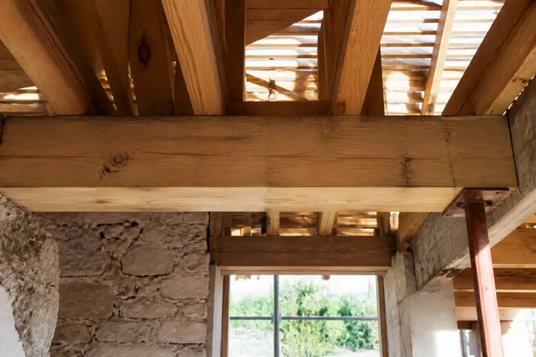Poutre de bois supportant une structure avec chevêtre, vue intérieure d'un chantier rénové