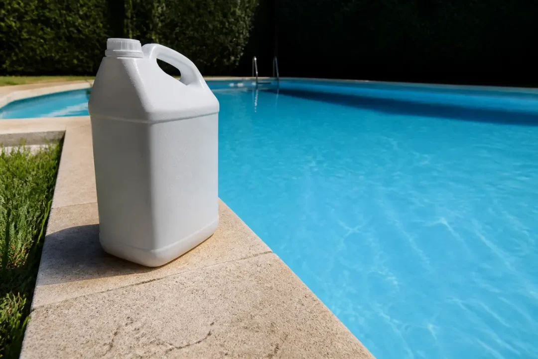 Bidon de javel pour piscine posé sur le bord d'une piscine bleue.