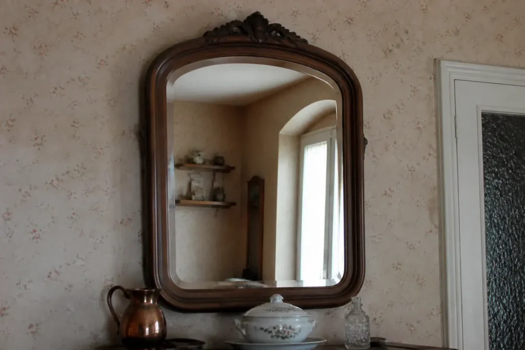 Grand miroir mural ancien reflétant une pièce décorée de céramiques élégantes et d'un beau mirrier