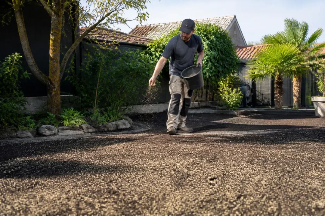 Homme semant pelouse sans retourner la terre dans un jardin ombragé et entouré d'arbres