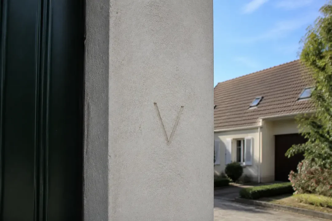 Lettre V gravée sur un mur, signe de cambriolage roumain typique d'avertissement.
